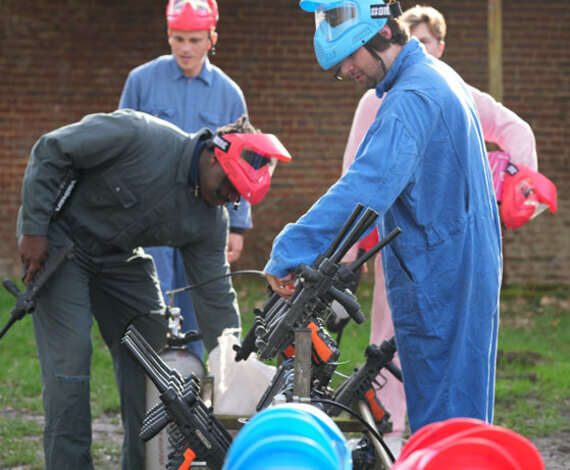Joueurs de paintball équipant leurs marqueurs avant une partie, portant combinaisons et masques de protection, en Brabant Wallon